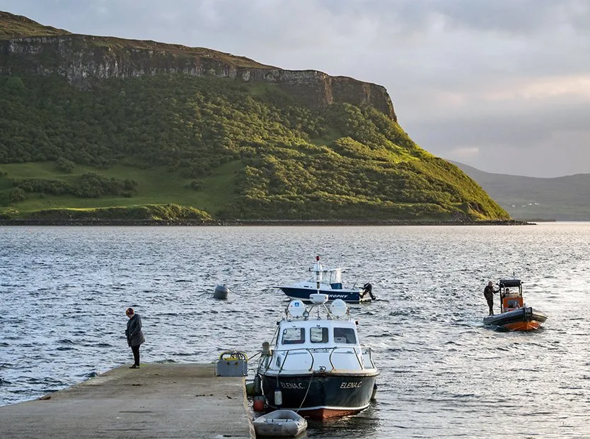 Working boats moored at the Loch Bay pier in the evening light