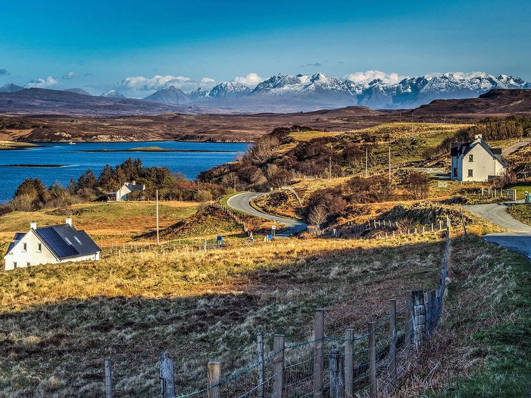 Crofting cottages and a single-track road on Skye, the Cuillin range beyond